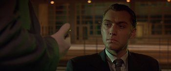 Movie still from “Gattaca” (1997), directed by Andrew Niccol – A man in a suit and tie holding a green object in front of him; Close Up shot, Over the shoulder angle