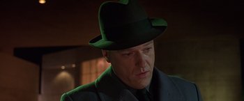 Movie still from “Gattaca” (1997), directed by Andrew Niccol – A person wearing a suit and a green hat; Close Up shot, Low angle
