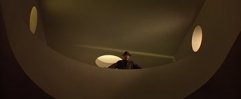 Movie still from “Gattaca” (1997), directed by Andrew Niccol – A man standing in a room with a hat on his head; Wide shot, Low angle