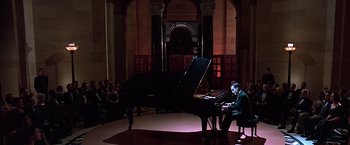 Movie still from “Gattaca” (1997), directed by Andrew Niccol – A man sitting in front of a grand piano in a room; Wide shot, High angle