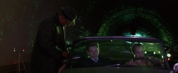 Movie still from “Gattaca” (1997), directed by Andrew Niccol – A man sitting in the back of a car next to another man; Medium shot, Low angle
