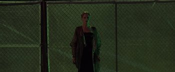 Movie still from “Gattaca” (1997), directed by Andrew Niccol – A woman standing in front of a chain link fence at night; Medium shot, Low angle