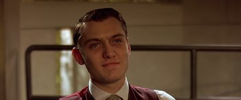 Movie still from “Gattaca” (1997), directed by Andrew Niccol – A man in a suit and tie looking at the camera; Close Up shot, Low angle