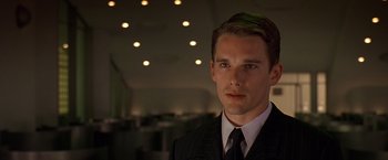 Movie still from “Gattaca” (1997), directed by Andrew Niccol – A man wearing a suit and tie in a room; Close Up shot, Low angle