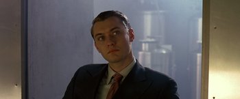 Movie still from “Gattaca” (1997), directed by Andrew Niccol – A man wearing a suit and tie in front of a window; Close Up shot, Low angle