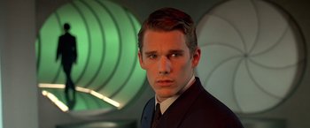 Movie still from “Gattaca” (1997), directed by Andrew Niccol – A man in a suit and tie in front of a green background; Close Up shot, Low angle