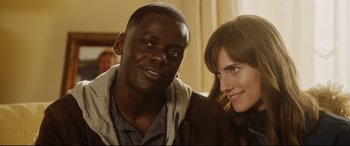 Movie still from “Get Out” (2017), directed by Jordan Peele – A man and a woman pose for a picture; Close Up shot, Over the shoulder angle
