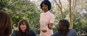 Movie still from “Get Out” (2017), directed by Jordan Peele – A woman holding a glass of liquid in her hand; Medium shot, Over the shoulder angle