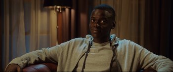 Movie still from “Get Out” (2017), directed by Jordan Peele – A person sitting in a chair wearing a hoodie; Medium shot, Over the shoulder angle