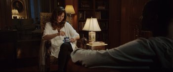 Movie still from “Get Out” (2017), directed by Jordan Peele – A woman sitting on a chair holding a cup; Medium shot, Over the shoulder angle