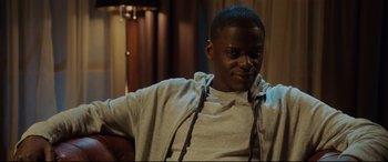 Movie still from “Get Out” (2017), directed by Jordan Peele – A man sitting in a chair wearing a hoodie; Medium shot, Over the shoulder angle