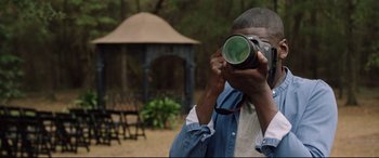 Movie still from “Get Out” (2017), directed by Jordan Peele – A man taking a picture with a camera outside; Close Up shot, Over the shoulder angle