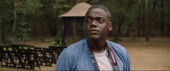 Movie still from “Get Out” (2017), directed by Jordan Peele – A person wearing a camera strap; Close Up shot, Over the shoulder angle