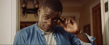 Movie still from “Get Out” (2017), directed by Jordan Peele – A person holding a cell phone up to his ear; Close Up shot, High angle