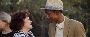 Movie still from “Get Out” (2017), directed by Jordan Peele – A man wearing a straw hat talking to a woman; Close Up shot, Over the shoulder angle