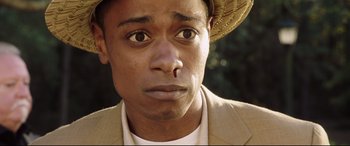 Movie still from “Get Out” (2017), directed by Jordan Peele – A person wearing a suit and a hat; Close Up shot, High angle