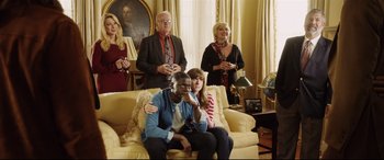 Movie still from “Get Out” (2017), directed by Jordan Peele – A group of people sitting on a couch in a living room; Medium shot, High angle