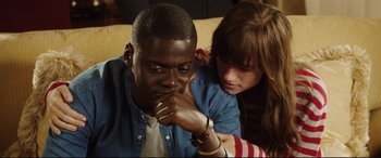 Movie still from “Get Out” (2017), directed by Jordan Peele – A man and a woman sitting next to each other on a couch; Close Up shot, Over the shoulder angle