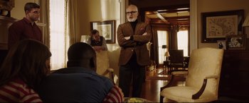 Movie still from “Get Out” (2017), directed by Jordan Peele – A man standing in a living room with his arms crossed; Medium shot, Over the shoulder angle