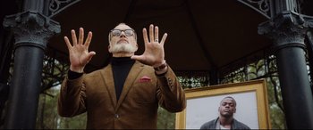 Movie still from “Get Out” (2017), directed by Jordan Peele – An older man wearing a brown suit and glasses; Medium shot, Low angle