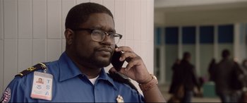 Movie still from “Get Out” (2017), directed by Jordan Peele – A police officer talking on a cell phone; Close Up shot, Low angle