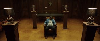Movie still from “Get Out” (2017), directed by Jordan Peele – A man sitting in a chair in front of a table; Wide shot, High angle