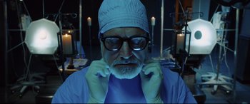 Movie still from “Get Out” (2017), directed by Jordan Peele – An old man wearing a surgical cap and glasses in the dark; Close Up shot, Low angle