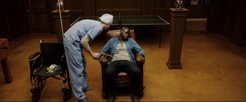 Movie still from “Get Out” (2017), directed by Jordan Peele – A man sitting in a chair being examined by a doctor; Medium shot, High angle