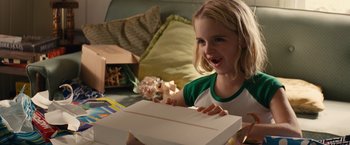 Movie still from “Gifted” (2017), directed by Marc Webb – A little girl holding a box and smiling; Close Up shot, High angle