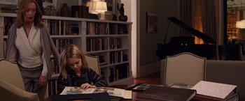 Movie still from “Gifted” (2017), directed by Marc Webb – A young girl sitting at a table looking at pictures; Medium shot, High angle