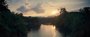 Movie still from “Gold” (2016), directed by Stephen Gaghan – The sun is setting over a body of water; Extreme Wide shot, High angle