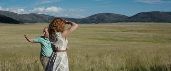 Movie still from “Gold” (2016), directed by Stephen Gaghan – A woman standing in the middle of an open field; Wide shot, Low angle
