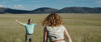 Movie still from “Gold” (2016), directed by Stephen Gaghan – A man and a woman are standing in a field; Wide shot, Over the shoulder angle