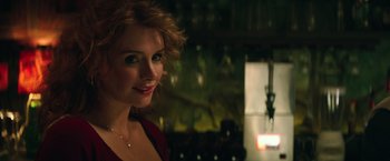 Movie still from “Gold” (2016), directed by Stephen Gaghan – A beautiful woman in a red shirt in a dark room; Close Up shot, Over the shoulder angle