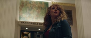 Movie still from “Gold” (2016), directed by Stephen Gaghan – A woman with curly hair standing in front of a painting; Close Up shot, Low angle