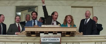 Movie still from “Gold” (2016), directed by Stephen Gaghan – A man raising his arm in the air in front of two other people; Medium shot, Low angle
