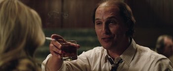 Movie still from “Gold” (2016), directed by Stephen Gaghan – A man holding a glass in his right hand; Close Up shot, Low angle
