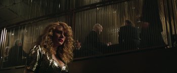 Movie still from “Gold” (2016), directed by Stephen Gaghan – A woman standing in front of a man in a black suit; Medium shot, Low angle