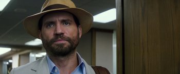 Movie still from “Gold” (2016), directed by Stephen Gaghan – A man with a beard wearing a straw hat; Close Up shot, Over the shoulder angle