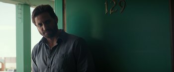 Movie still from “Gold” (2016), directed by Stephen Gaghan – A man standing in front of a green wall; Close Up shot, Low angle