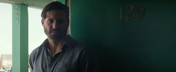 Movie still from “Gold” (2016), directed by Stephen Gaghan – A man with a beard standing in front of a green wall; Close Up shot, Over the shoulder angle