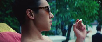 Movie still from “Gold” (2016), directed by Stephen Gaghan – A young man wearing glasses looking to his left; Close Up shot, Over the shoulder angle