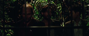 Movie still from “Gold” (2016), directed by Stephen Gaghan – Two men are standing behind a fence in the dark; Medium shot, Over the shoulder angle