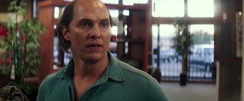 Movie still from “Gold” (2016), directed by Stephen Gaghan – A man with a goatee is standing in front of a window; Close Up shot, Over the shoulder angle