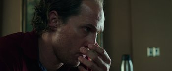 Movie still from “Gold” (2016), directed by Stephen Gaghan – A person with his hand to his face; Close Up shot, Low angle