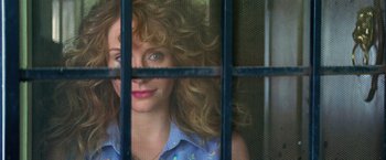 Movie still from “Gold” (2016), directed by Stephen Gaghan – A woman with curly hair looking through a window; Close Up shot, Low angle