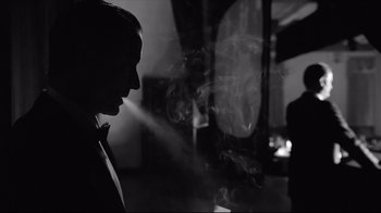 Movie still from “Good Night, and Good Luck.” (2005), directed by George Clooney – A man smoking a cigarette while wearing a tie; Medium shot, Low angle