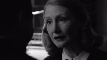 Movie still from “Good Night, and Good Luck.” (2005), directed by George Clooney – An older woman with blonde hair wearing a black tie; Close Up shot, Over the shoulder angle