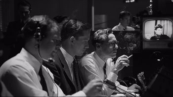 Movie still from “Good Night, and Good Luck.” (2005), directed by George Clooney – A black and white photo of a group of men sitting at a table; Medium shot, High angle
