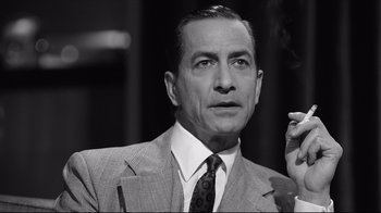 Movie still from “Good Night, and Good Luck.” (2005), directed by George Clooney – An older man smoking a cigarette while wearing a suit; Close Up shot, Low angle